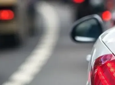 Cars queuing on the road in traffic with brake lights on. 